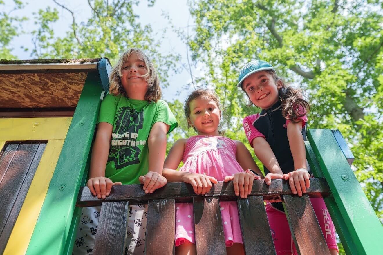 Three smiling children playing together on their first days at an international summer camp