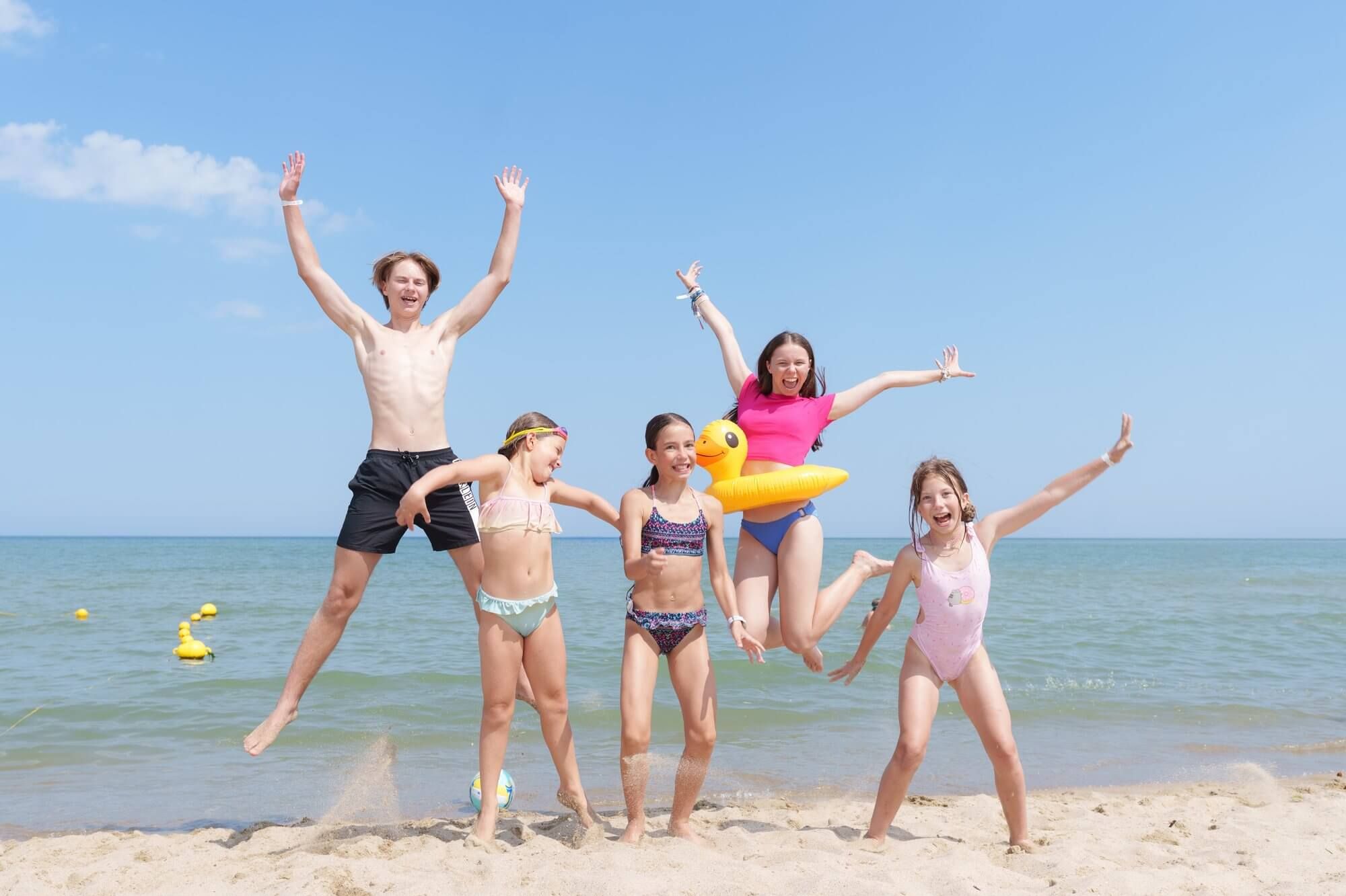 Children jumping for joy on the beach at an international summer camp on the Black Sea