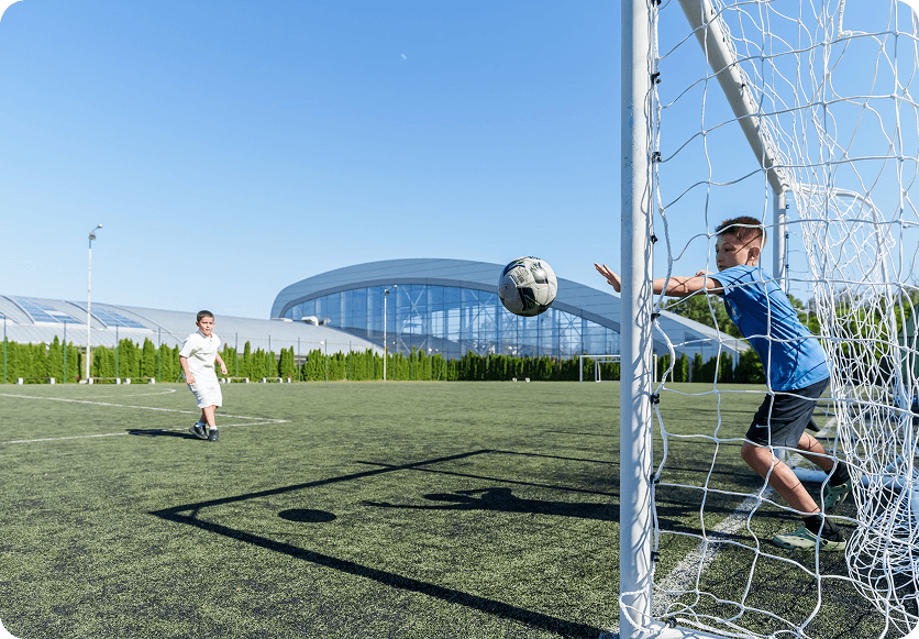 Antrenör genç futbolcuyu sahada eğitiyor