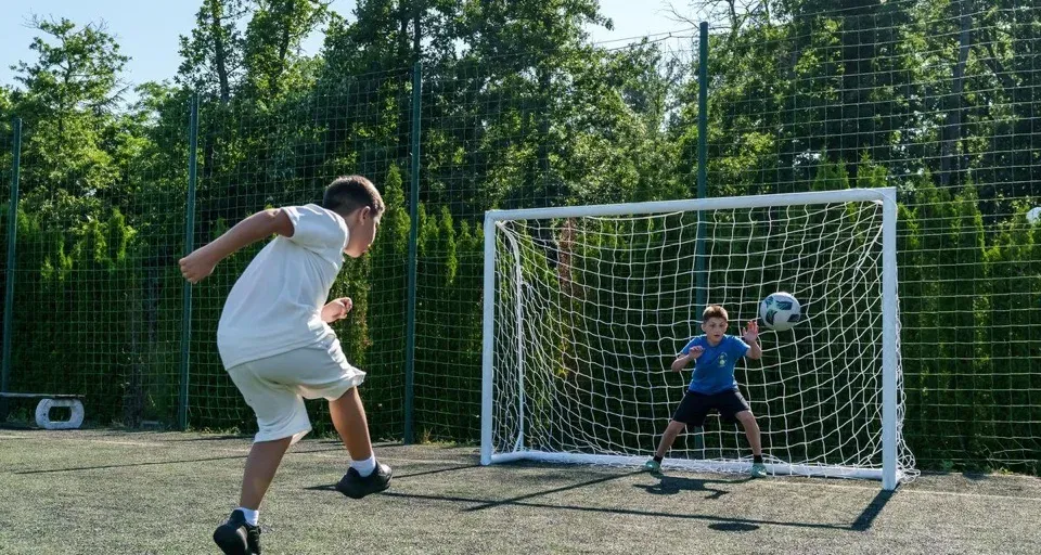Coach training a young football player on the pitch