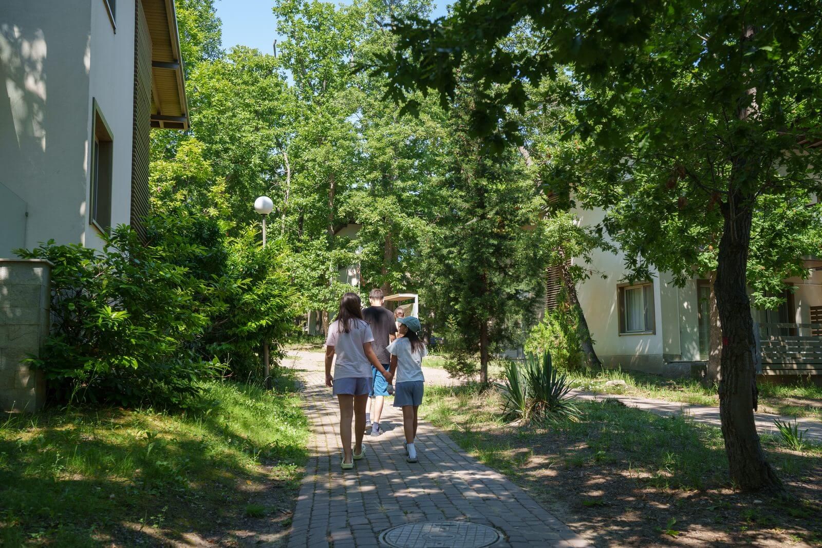 Children walking through a green, enclosed summer camp campus in a nature reserve