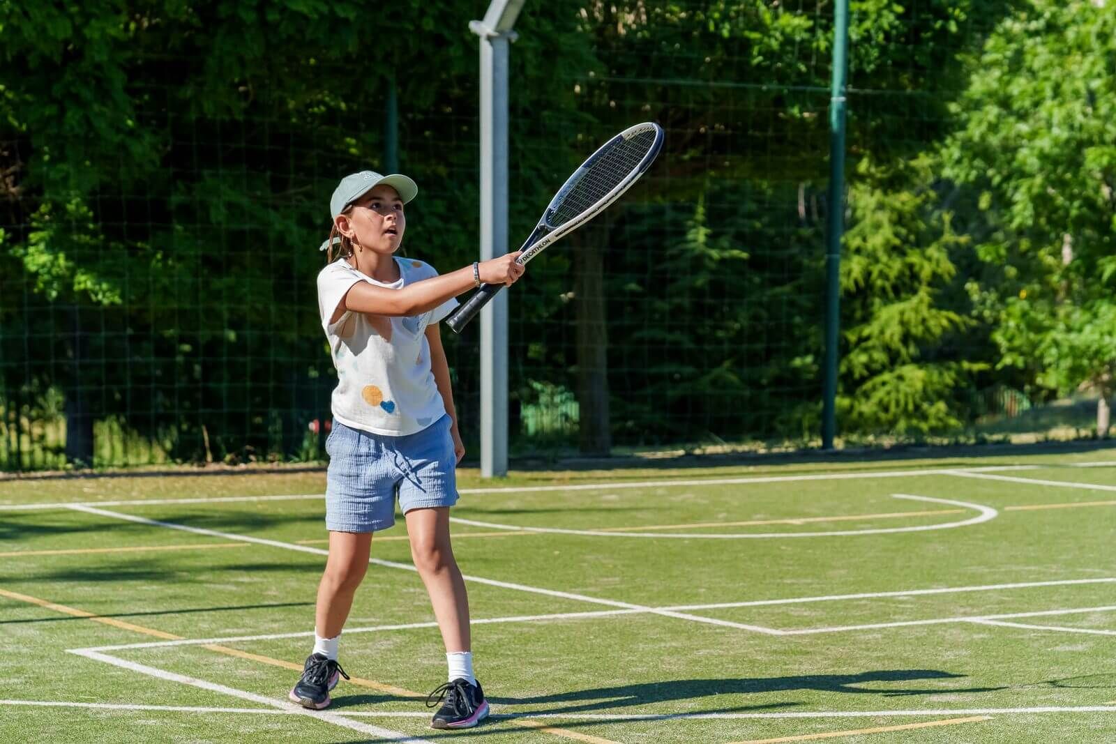 A young child playing tennis at a summer camp for children
