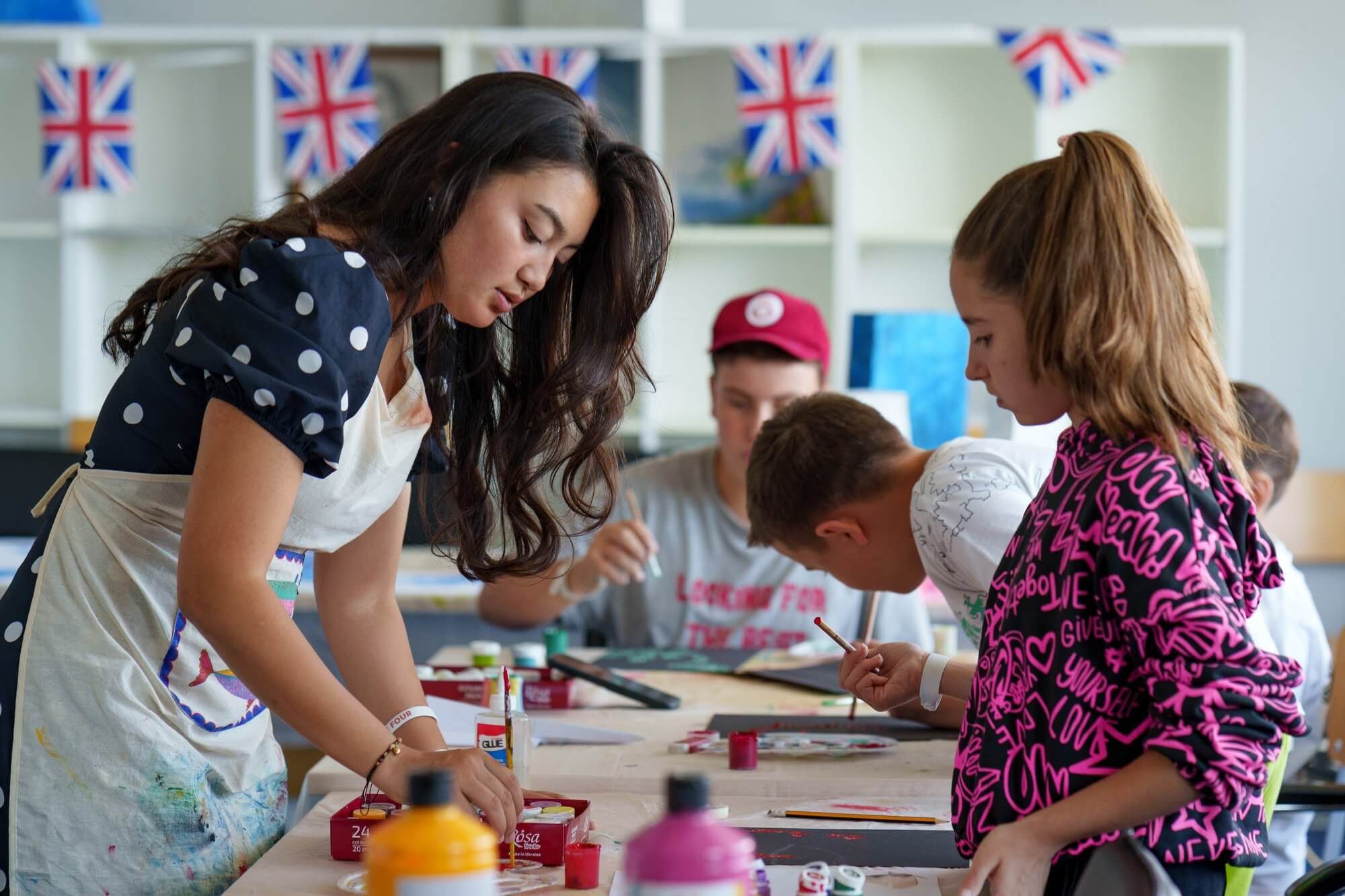 An art teacher helping children paint during a workshop at VIEC summer camp