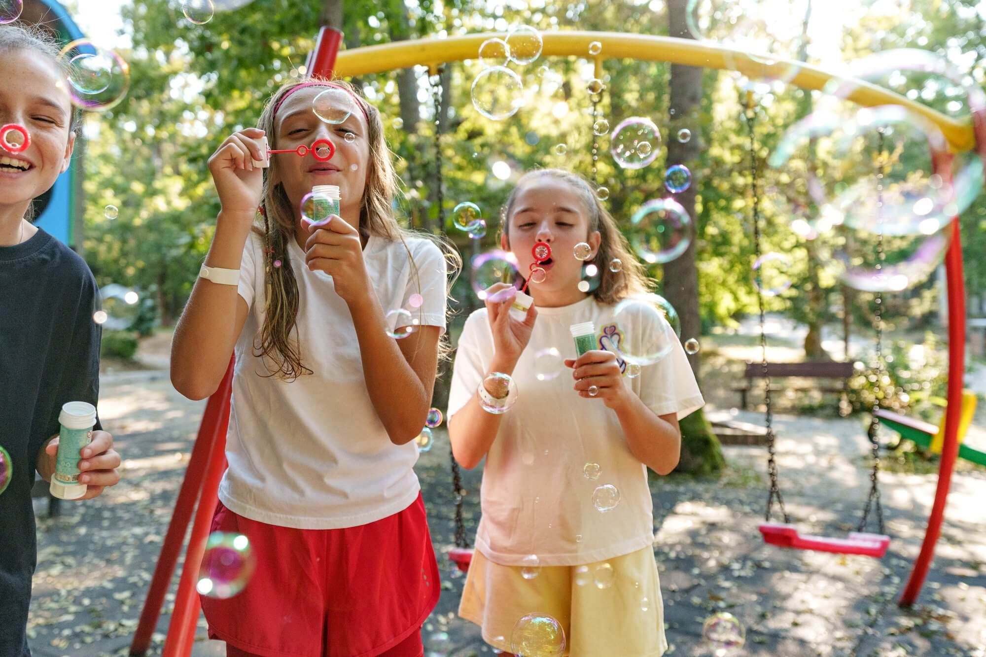 Two girls laughing while blowing soap bubbles at VIEC summer camp