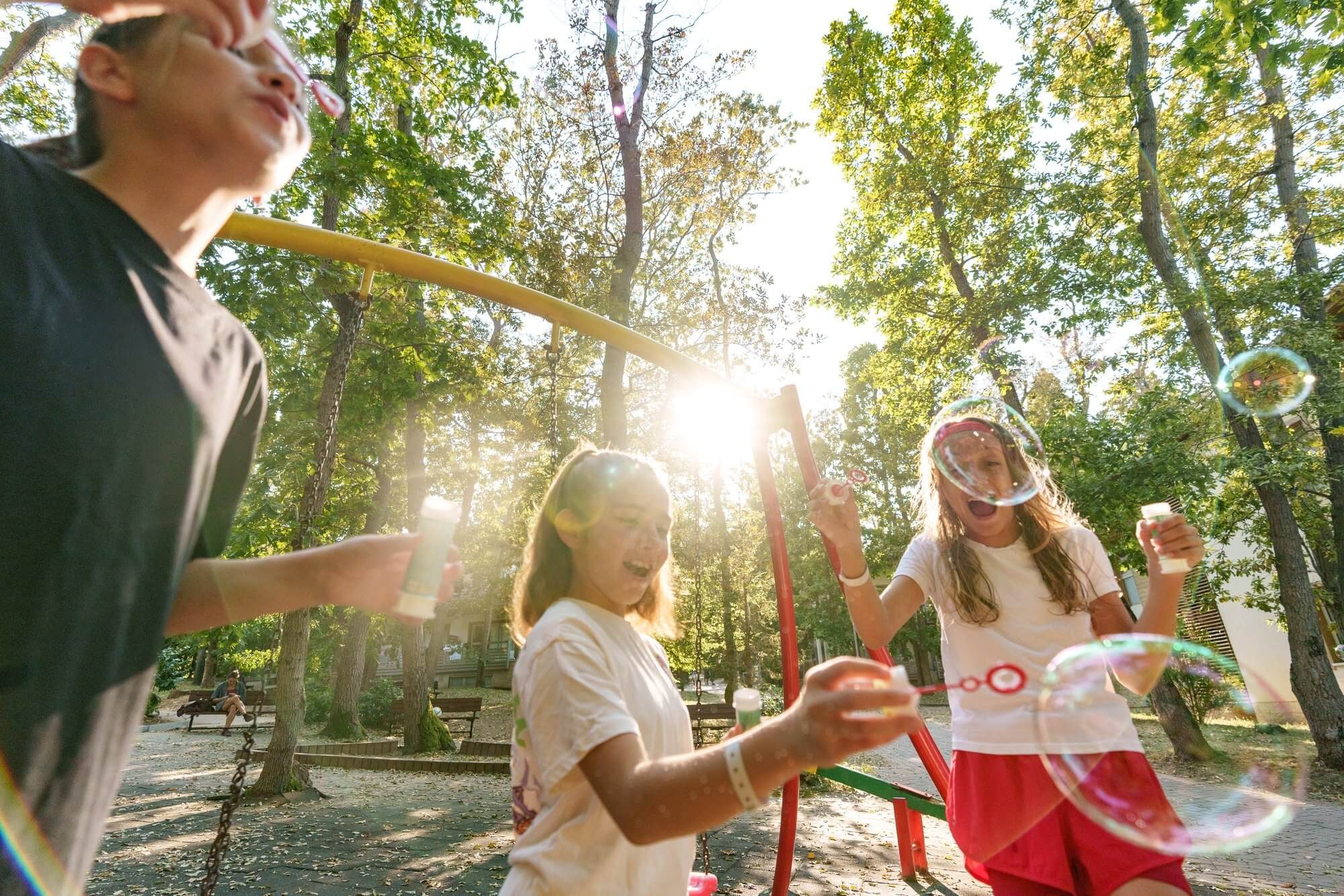 Children chasing soap bubbles outdoors in the afternoon sun at VIEC summer camp