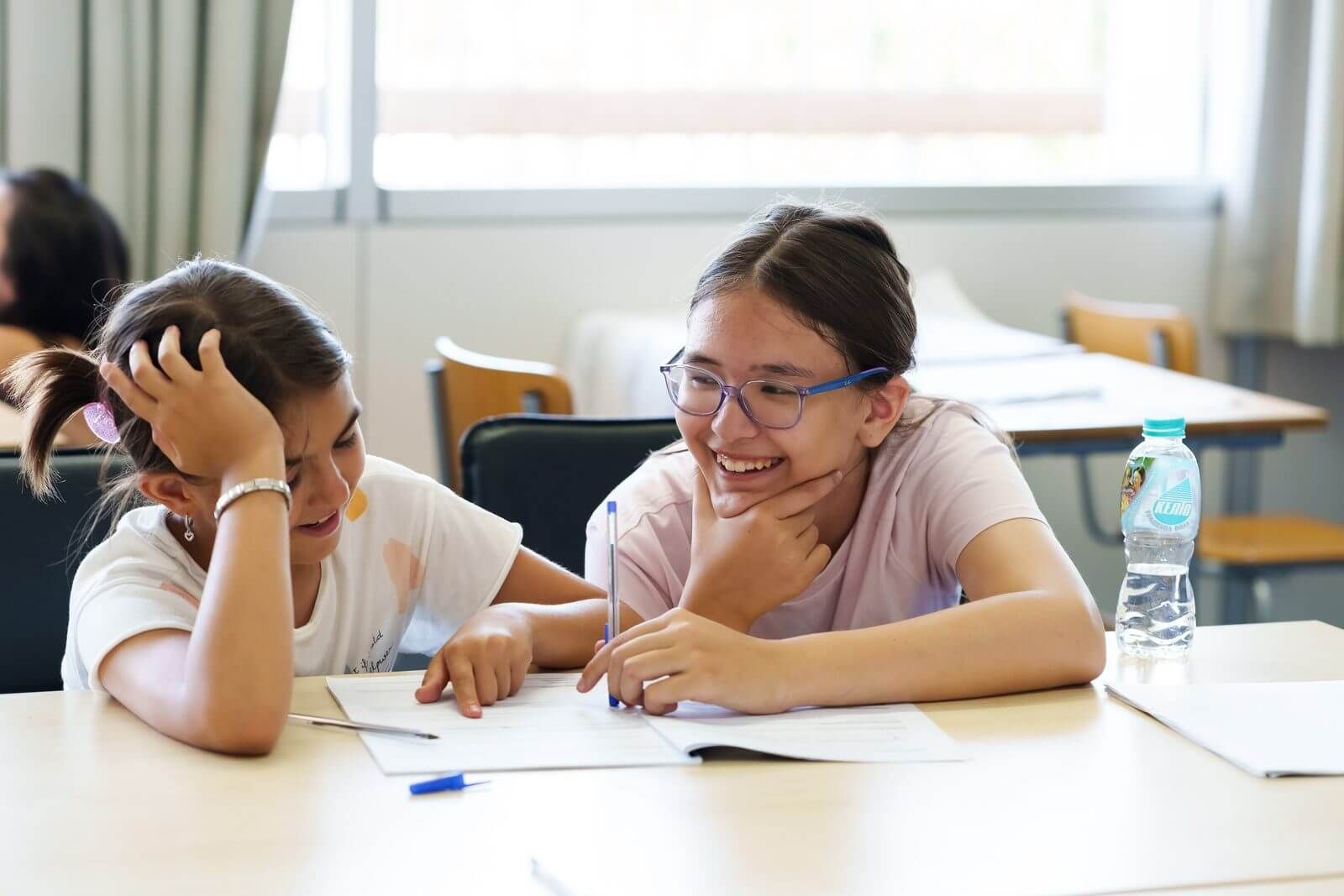 Two children laughing together while working at an international English summer camp